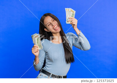 Happy woman holding fan of cash money dollar banknotes celebrate success win victory wealth dancing 125371025