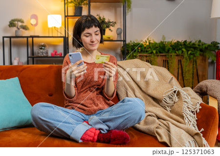 Happy young woman doing payments online or shopping in internet store holding banking credit card 125371063