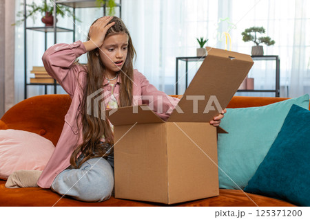 Angry dissatisfied shopper girl unpacking parcel feeling upset mistake delivery broken purchase gift Angry dissatisfied shopper girl unpacking parcel feeling upset mistake delivery broken purchase gift 125371200