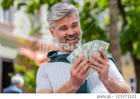 Rich happy mature man counting money income earnings cash, calculate banknotes salary on city street Rich happy mature man counting money income earnings cash, calculate banknotes salary on city street 125371223