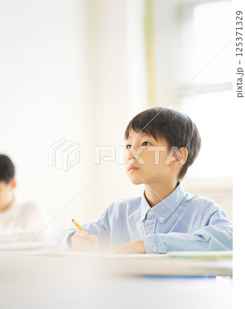 教室で勉強中の男子小学生｜真剣な表情で前を見る 125371329