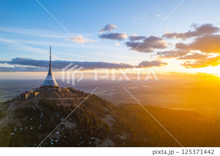 Springtime at Jested in Liberec offers breathtaking sunset views. The sun casts warm hues over the landscape, illuminating the iconic tower and surrounding nature. 125371442