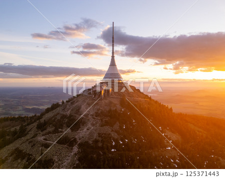 At sunset, the Jested mountain stands majestically in Liberec, Czechia, showcasing its iconic tower illuminated by soft golden light, surrounded by beautiful spring scenery. At sunset, the Jested mountain stands majestically in Liberec, Czechia, showcasing its iconic tower illuminated by soft golden light, surrounded by beautiful spring scenery. 125371443