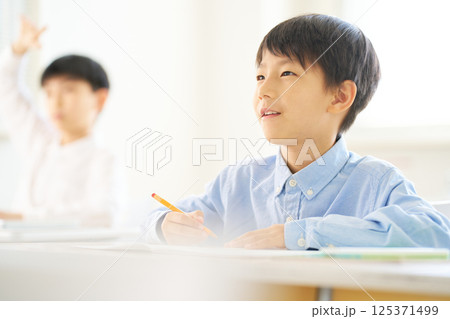 教室で勉強中の男子小学生｜笑顔で前を見る 125371499