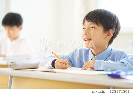 教室で勉強中の男子小学生|明るい表情で前を見る 教室で勉強中の男子小学生|明るい表情で前を見る 125371501
