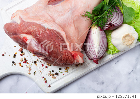 Raw pork knuckle, on a wooden chopping board, with spices, close-up, top view, no people, Raw pork knuckle, on a wooden chopping board, with spices, close-up, top view, no people, 125371541