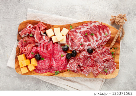 Assorted, sliced meat appetizer, prosciutto, salami and ham, with cheese and olives, on a wooden board, breakfast, top view, close-up, no people, Assorted, sliced meat appetizer, prosciutto, salami and ham, with cheese and olives, on a wooden board, breakfast, top view, close-up, no people, 125371562