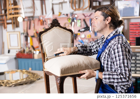 Male carpenter working on making vintage chair in workshop 125371656