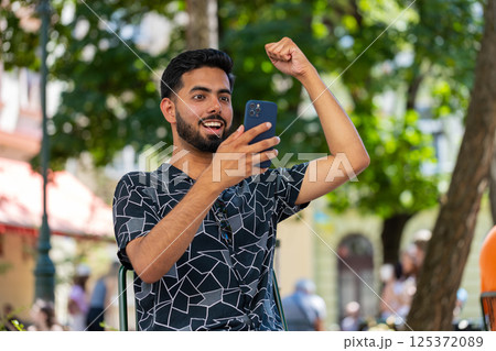 Indian man using mobile smartphone celebrating win good message online news victory on city street 125372089