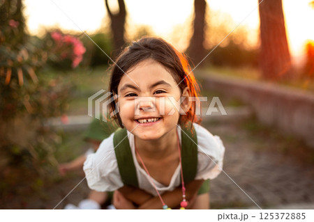 close-up portrait of smiling girl standing in the park looking at camera 125372885