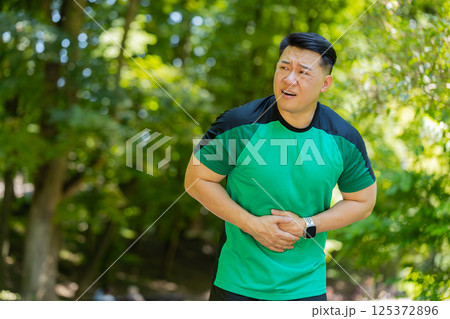 Asian middle-aged runner man feeling sudden strong abdominal stomach ache gastritis problem diarrhea 125372896