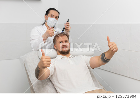 Trichologist doing man improve hair growth procedure, dermapen microneedling, vitamin injections Trichologist doing man improve hair growth procedure, dermapen microneedling, vitamin injections 125372904