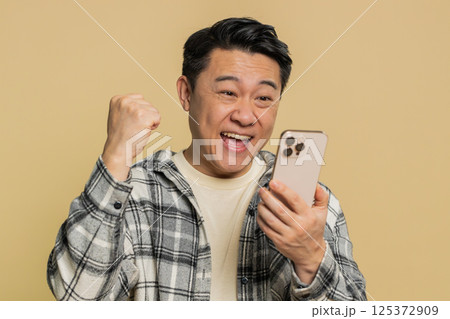 Happy excited winner man use smartphone celebrating success winning play game good lottery news Happy excited winner man use smartphone celebrating success winning play game good lottery news 125372909