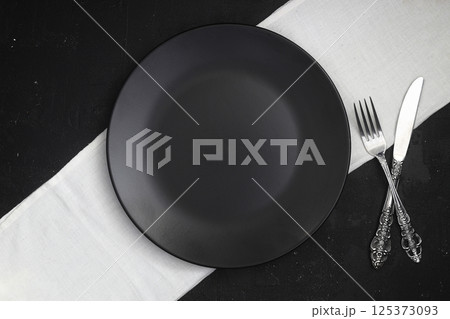 Empty black slate plate on dark stone table. Food background for menu, recipe. Table setting. Empty black slate plate on dark stone table. Food background for menu, recipe. Table setting. 125373093