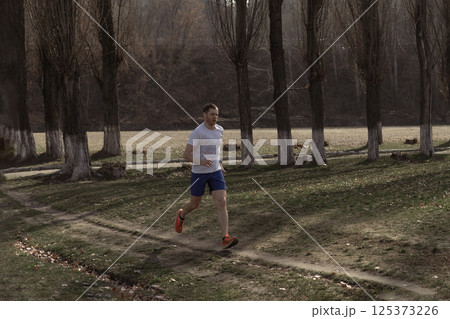 A male professional runner is running outside the city A male professional runner is running outside the city 125373226