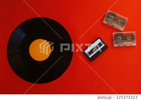 Audio cassette, vinyl record on a red background. Retro style. Top view 125373323