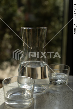 a glass container with water and two glasses 125373331