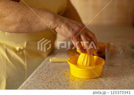 Close-up of a mature woman's hand squeezing juice from an orange Close-up of a mature woman's hand squeezing juice from an orange 125373341