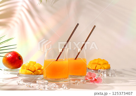 Modern still life with tropical fruits.Homemade cocktail, juice or lemonade with mango slices and ice on sunny kitchen table.Summer party concept and Detox diet, Restaurant menu 125373407