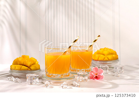 Modern still life with tropical fruits.Homemade cocktail, juice or lemonade with mango slices and ice on sunny kitchen table.Summer party concept and Detox diet, Restaurant menu 125373410
