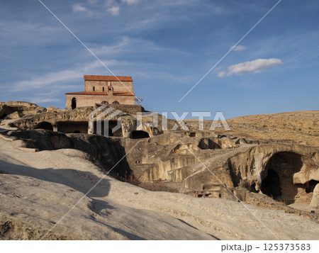 Historic church perched above rock carved cave dwellings in uplistsikhe, revealing georgia's ancient architectural heritage and cultural landscape Historic church perched above rock carved cave dwellings in uplistsikhe, revealing georgia's ancient architectural heritage and cultural landscape 125373583