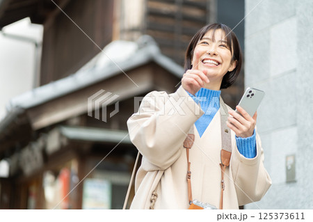 昔ながらの街並みを見る女性　旅行をするコートの女性　一人旅 125373611
