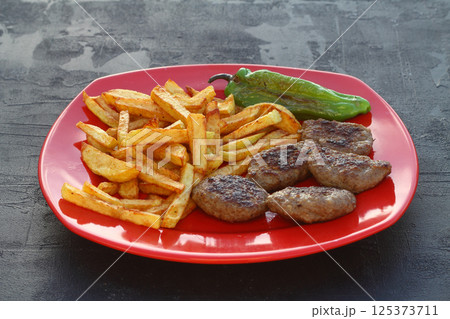 meatballs and potatoes on a red plate on black background 125373711