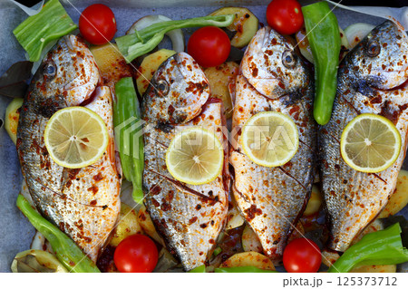 Baked in oven sea fish dorado or sea bream with lime, pepper, tomato, olives and onion Baked in oven sea fish dorado or sea bream with lime, pepper, tomato, olives and onion 125373712
