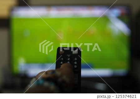 A person with a TV remote controls the remote control to switch channels to watch TV shows. A person with a TV remote controls the remote control to switch channels to watch TV shows. 125374621