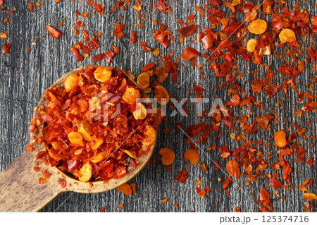 Wooden bowl with crushed chili pepper and fresh red chili pepper on old table. Selective focus. 125374716