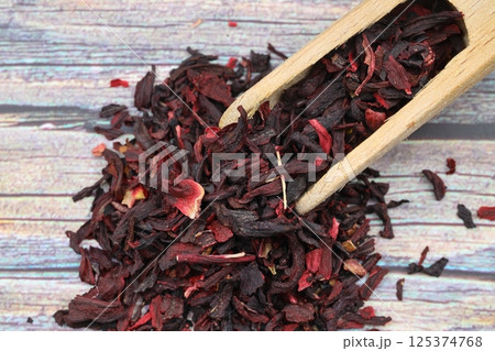 Karkade tea. Hibiscus tea leaves in wooden scoop isolated on wooden background. File contains clipping path. Top view. 125374768