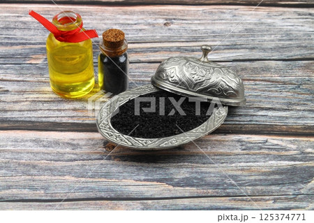 Black cumin seeds and essential oil with bowl and wooden shovel or spoon. Nigella Sativa in glass bottle. Organic herbal medicine for many diseases Black cumin seeds and essential oil with bowl and wooden shovel or spoon. Nigella Sativa in glass bottle. Organic herbal medicine for many diseases 125374771