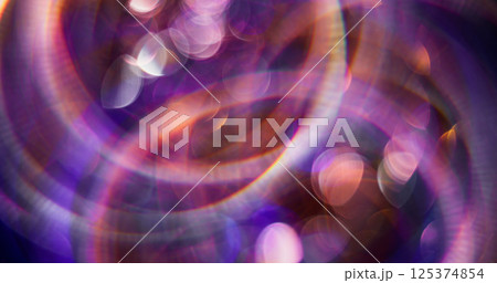 Defocused light. Rays flares. Bright sparkling purple color particles lens flash motion on blurred background with bokeh effect. Defocused light. Rays flares. Bright sparkling purple color particles lens flash motion on blurred background with bokeh effect. 125374854