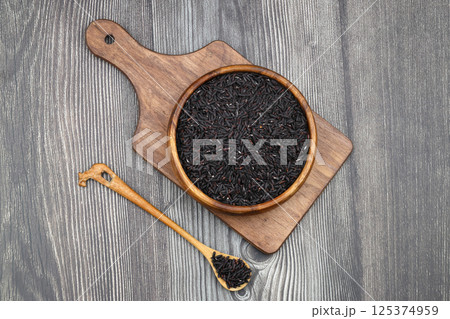 pile of black rice in a wooden bowl on a wooden table close-up 125374959