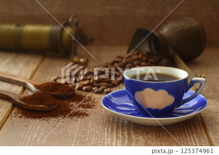 Coffee beans and ground coffee in wooden spoons on brown background. Flat lay. 125374961