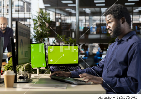 African american employee uses green screen and evaluating performance metrics, working with statistics and company numbers to build a new strategy for development. Office life. 125375643