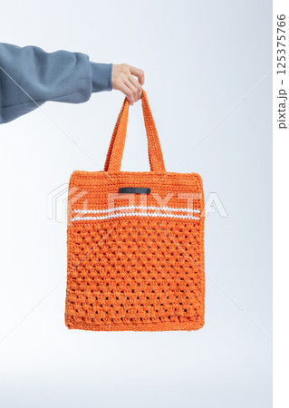 Beautiful woman of model appearance. Girl in grey sweatshirt with orange color bag on light background. Pretty female with trendy makeup posing in studio. Vertical photo. High quality photo Beautiful woman of model appearance. Girl in grey sweatshirt with orange color bag on light background. Pretty female with trendy makeup posing in studio. Vertical photo. High quality photo 125375766