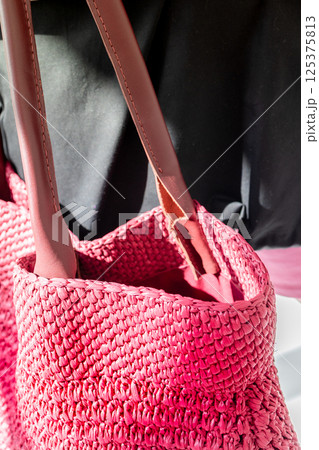 Female hand holding fashionable red woven bag. Fashion and luxury accessories. Vertical photo. High quality photo 125375813