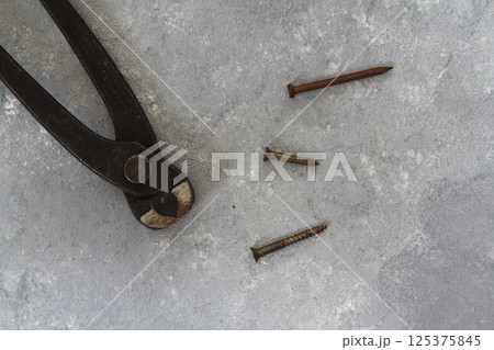 Old rusty pliers and nails on a stone background. View from above Old rusty pliers and nails on a stone background. View from above 125375845