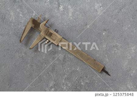 very old used rusty iron calipers isolated on stone background. 125375848