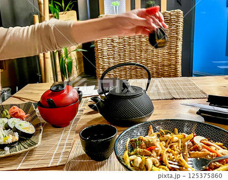 Spaghetti with chicken, mushrooms and sesame seeds on a plate in a asian food restaurant with teapot and chopsticks Spaghetti with chicken, mushrooms and sesame seeds on a plate in a asian food restaurant with teapot and chopsticks 125375860