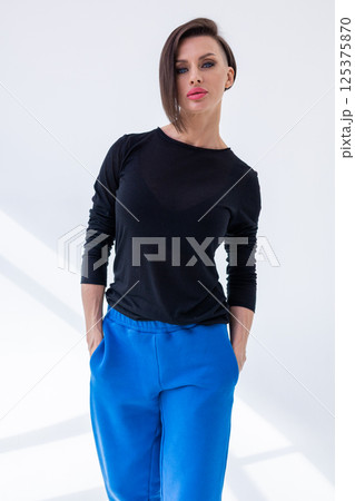Portrait of young woman in black sweatshirt and blue pants close-up on white background. Studio photography. Vertical photo. High quality photo 125375870