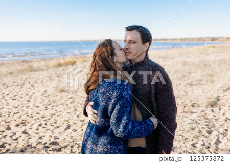 Loving couple walks on beach along sea on sunny autumn day. Weekend and lifestyle concept. High quality photo 125375872