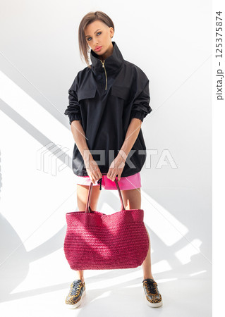 Beautiful woman holding fashionable red woven bag. Fashion and luxury accessories. Vertical photo. High quality photo 125375874