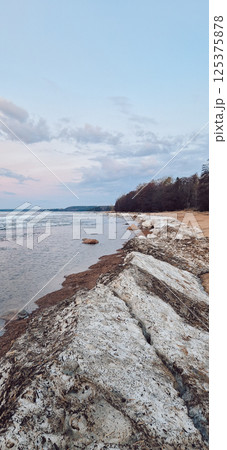 Peaceful scene of ice floes drifting in calm ocean waters with stunning sunset sky. Reflective water surface captures colorful clouds, evoking serenity and tranquility. Vertical photo Peaceful scene of ice floes drifting in calm ocean waters with stunning sunset sky. Reflective water surface captures colorful clouds, evoking serenity and tranquility. Vertical photo 125375878