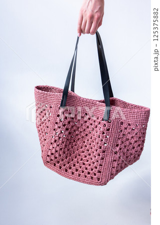 Female hand holding fashionable pink woven bag. Fashion and luxury accessories. Vertical photo. High quality photo 125375882