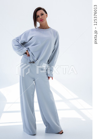 Young woman in gray sweatshirt and pants on white background. Studio photography. Vertical photo. High quality photo 125376013