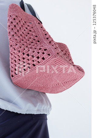 Female hand holding fashionable pink woven bag. Fashion and luxury accessories. Bottom view. Vertical photo. High quality photo 125376048