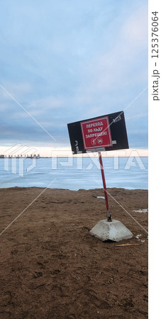 Winter landscape. Red warning sign Danger of going out on ice. Walking on melted snow on bay is dangerous. Vertical photo. High quality photo Winter landscape. Red warning sign Danger of going out on ice. Walking on melted snow on bay is dangerous. Vertical photo. High quality photo 125376064