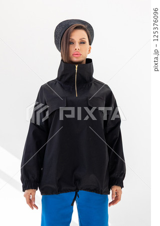 Elegant woman in black windbreaker jacket, blue pants and nautical hat on white background. Fashionable female in ocean French style. tudio photography. Vertical photo. High quality photo Elegant woman in black windbreaker jacket, blue pants and nautical hat on white background. Fashionable female in ocean French style. tudio photography. Vertical photo. High quality photo 125376096